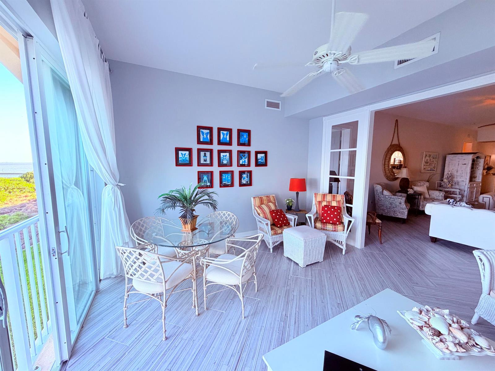 A sunroom features a glass dining table, wicker chairs, and a gallery wall of framed art — 3 E Harbour Isle Drive E # 204, Fort Pierce FL 34949, FORT PIERCE, FL