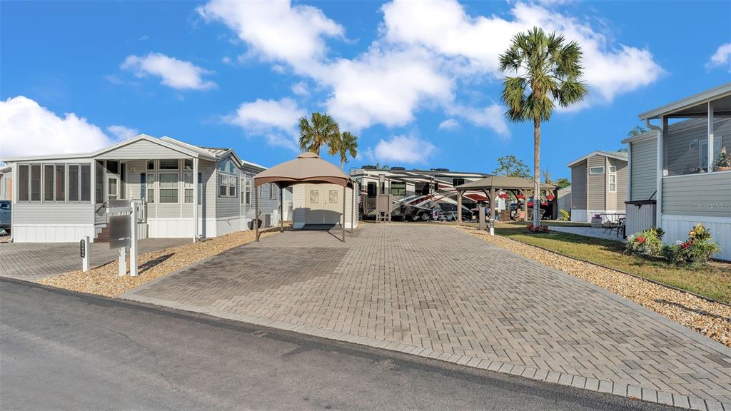 A paved driveway sits between two manufactured homes with a gazebo and parked recreational vehicle — 2436 CITRUS TREE ROAD, CLERMONT, FL