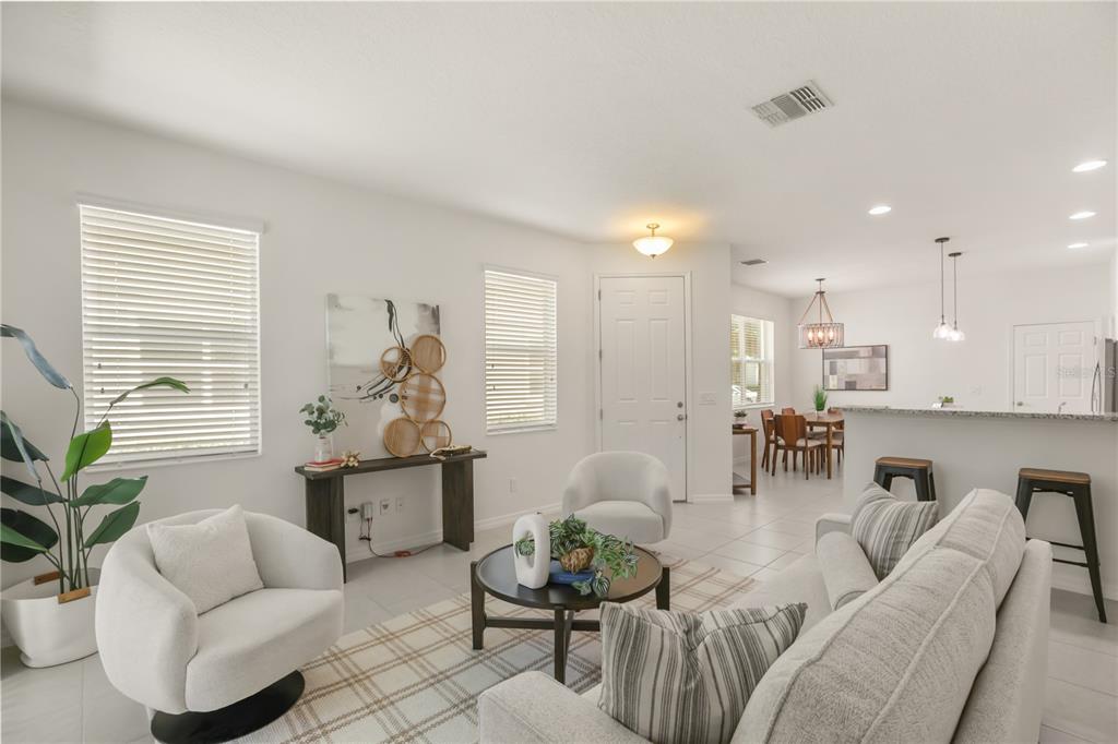 A bright open-concept living room features a sofa, two armchairs, and a dining area — 2340 BRITWELL PLACE, SANFORD, FL