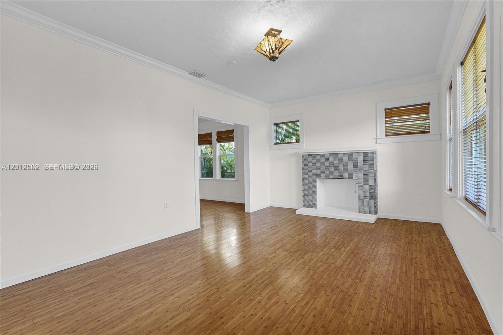 A living room features hardwood floors, a tiled fireplace, and a doorway to another room — 126 NW 48th St # 0, Miami FL 33127, MIAMI, FL