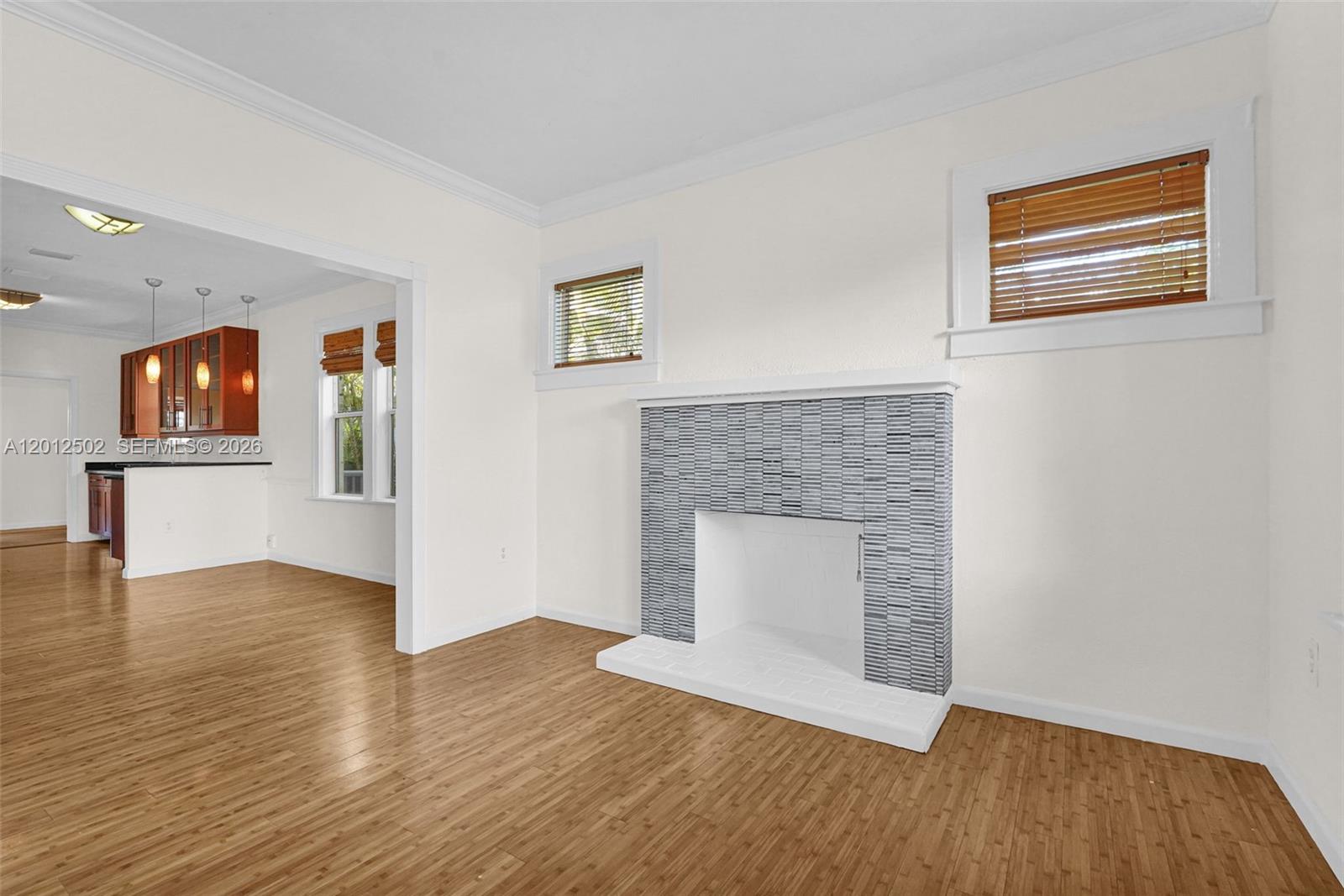 A living room features a tiled fireplace, wood flooring, and an adjacent kitchen area — 126 NW 48th St # 0, Miami FL 33127, MIAMI, FL
