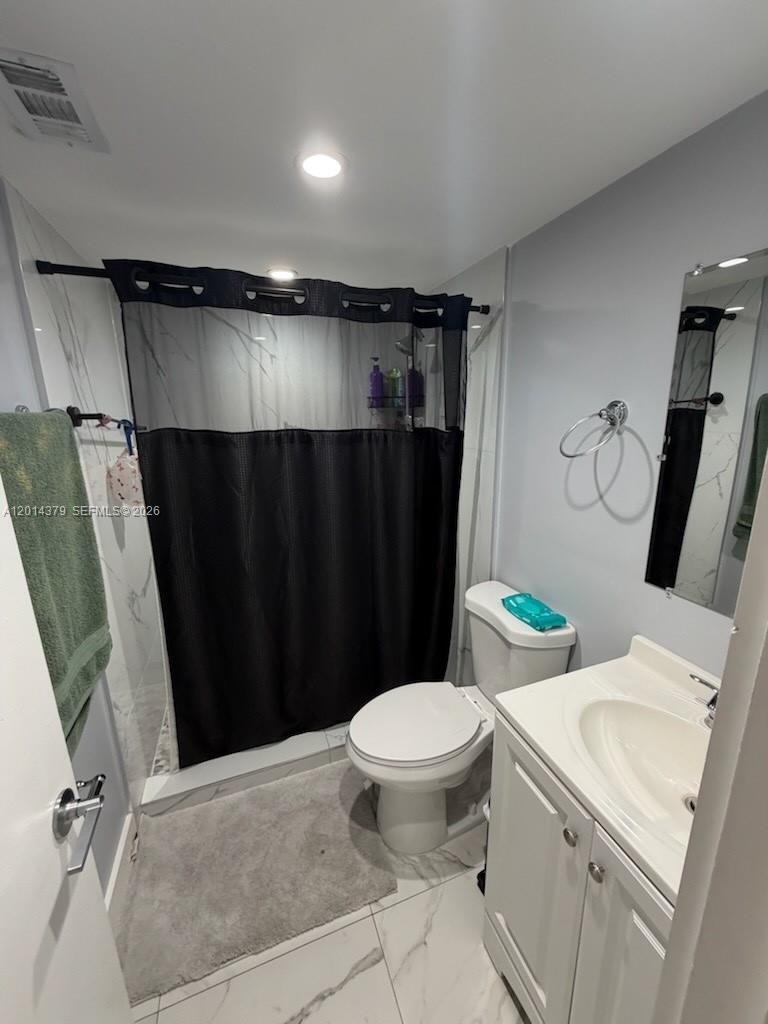 A bathroom features a white vanity, a toilet, and a shower with a black curtain — 5033 NW 7th St # 209, Miami FL 33126, MIAMI, FL