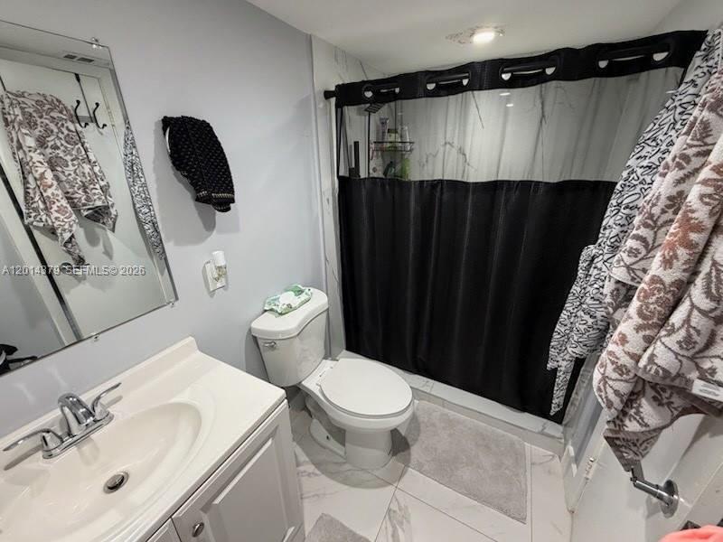 A bathroom features a white vanity, a toilet, and a shower with a black curtain — 5033 NW 7th St # 209, Miami FL 33126, MIAMI, FL