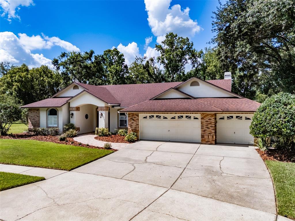 A single-story house with a brick and stucco exterior, a three-car garage, and a driveway — 507 SURREY LANE, LUTZ, FL