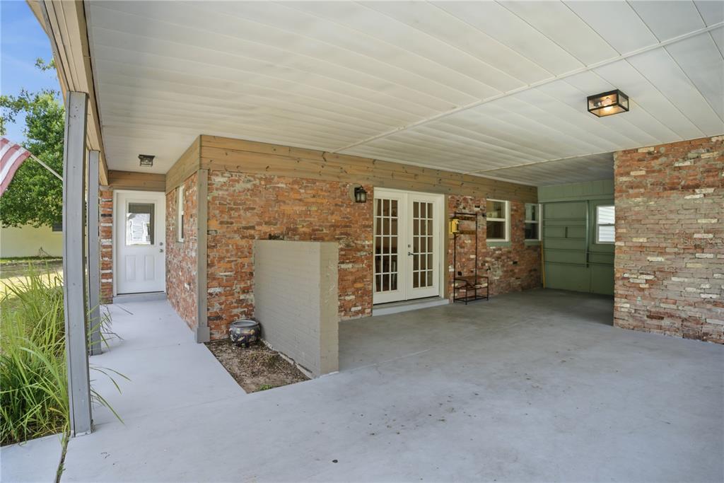 A covered carport features a brick exterior, concrete flooring, and a set of French doors — 8 SILVER WAY, OCALA, FL