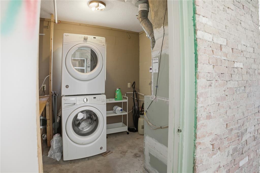 A laundry room features a stacked washer and dryer set next to an HVAC unit — 8 SILVER WAY, OCALA, FL