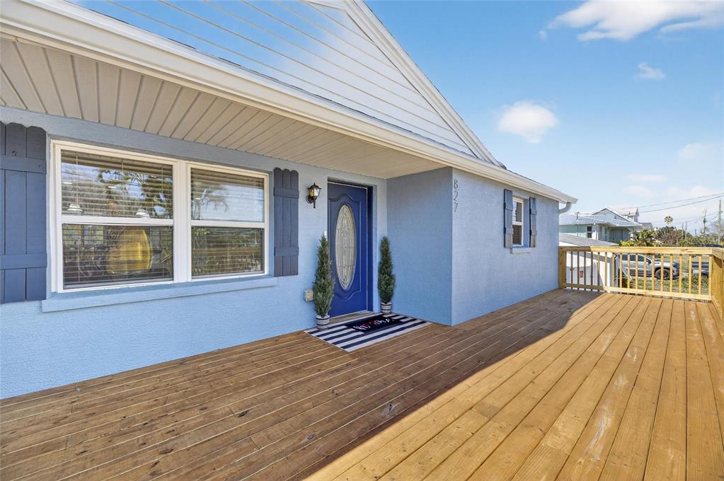 A blue house features a large wooden deck and a front door with a window — 827 SEABREEZE DRIVE, RUSKIN, FL