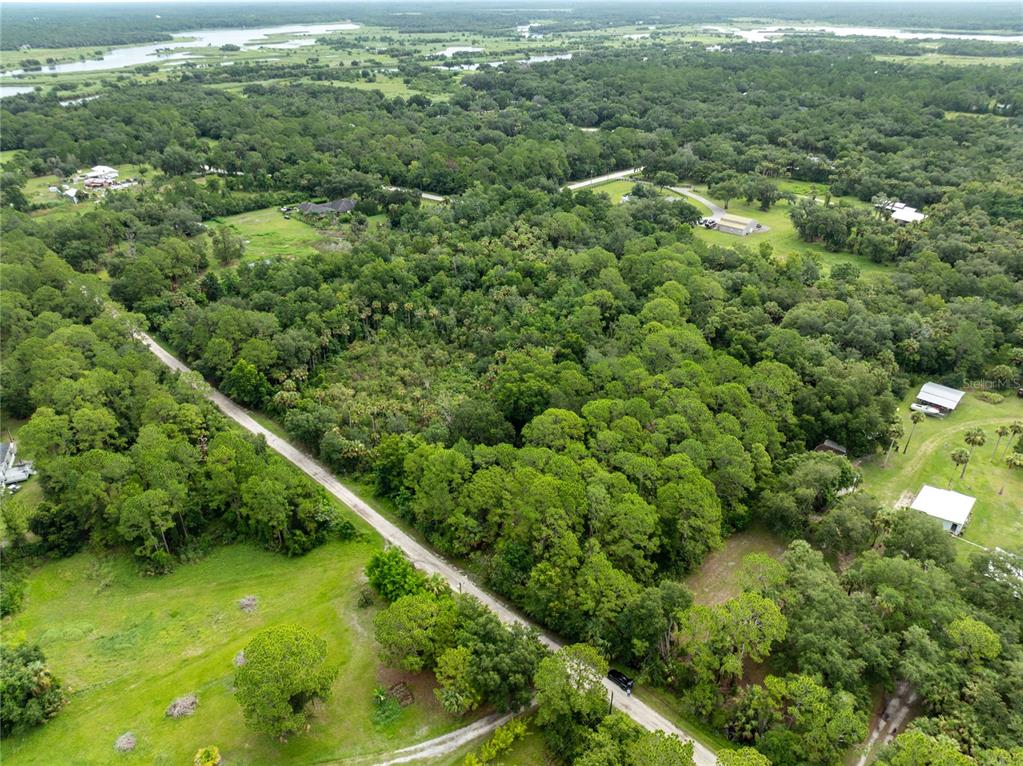 An aerial view shows a wooded lot bordered by a road and nearby rural homes — 2750 PERCH ROAD, GENEVA, FL