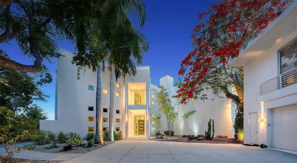 A modern white multi-story home features a paved driveway, palm trees, and a flowering tree — 4317 MIDNIGHT PASS ROAD, SARASOTA, FL