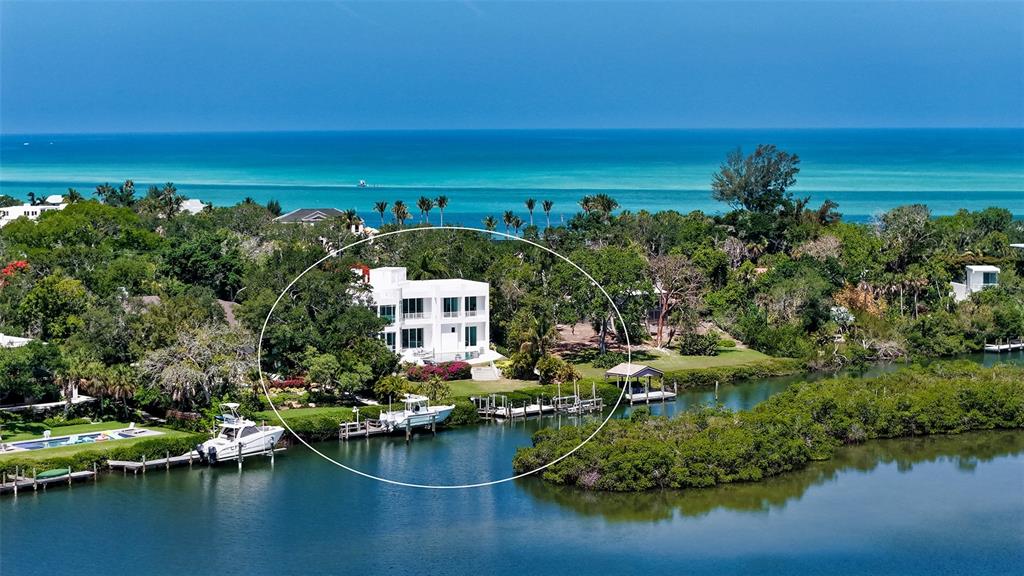 A modern white multi-story house features a concrete driveway, palm trees, and flowering trees — 4317 MIDNIGHT PASS ROAD, SARASOTA, FL