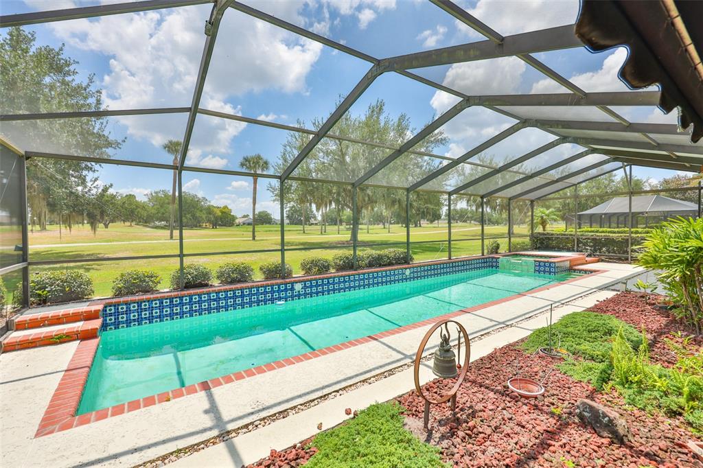 A screened-in swimming pool and spa overlook a grassy golf course under a blue sky — 1927 E VIEW DRIVE, SUN CITY CENTER, FL