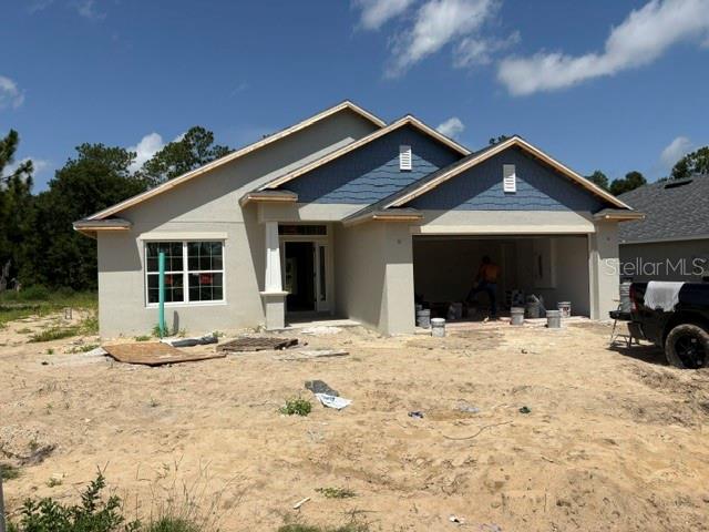A newly constructed single-story house with a two-car garage and unfinished sandy yard — 7722 SW 180TH CIRCLE, DUNNELLON, FL