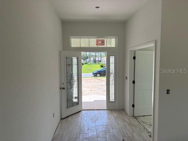 An entryway with light-colored tile flooring, a glass-paneled front door, and an interior doorway — 7722 SW 180TH CIRCLE, DUNNELLON, FL