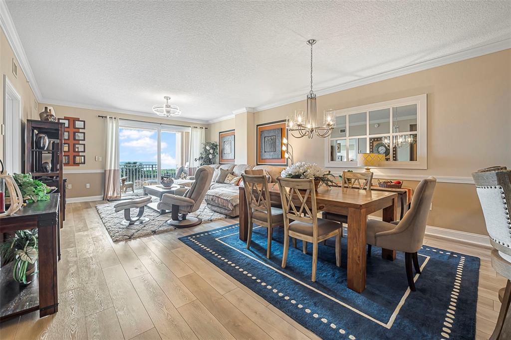 A living and dining room with wood floors, a blue area rug, and balcony views — 60 SURFVIEW DRIVE UNIT 208, PALM COAST, FL