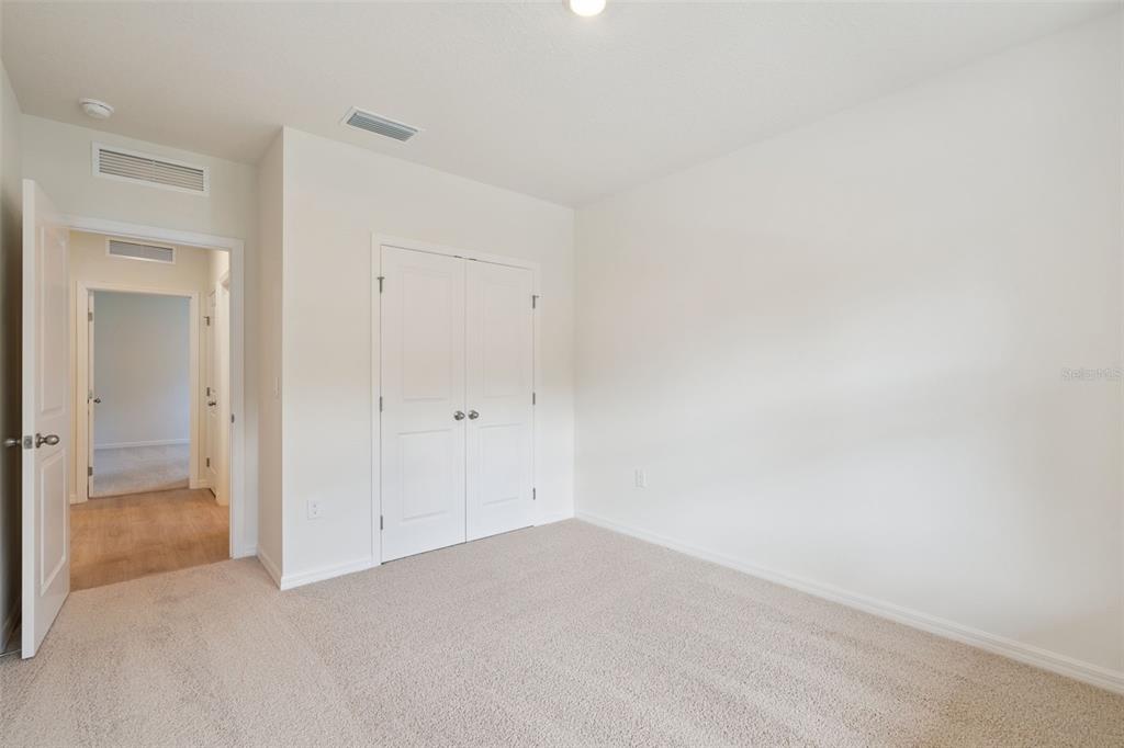 An empty bedroom features beige carpet, white walls, and a double-door closet — 1148 MORFONTAINE STREET, DAYTONA BEACH, FL