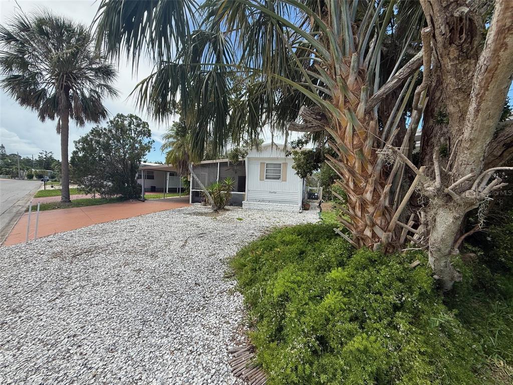 A white mobile home with a screened porch sits behind a gravel driveway and palm trees — 4845 BOCA RATON AVENUE, SARASOTA, FL