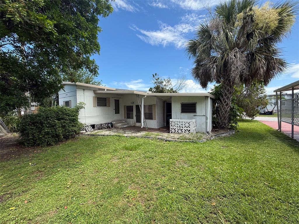 A single-story mobile home with white siding and a palm tree in the yard — 4845 BOCA RATON AVENUE, SARASOTA, FL