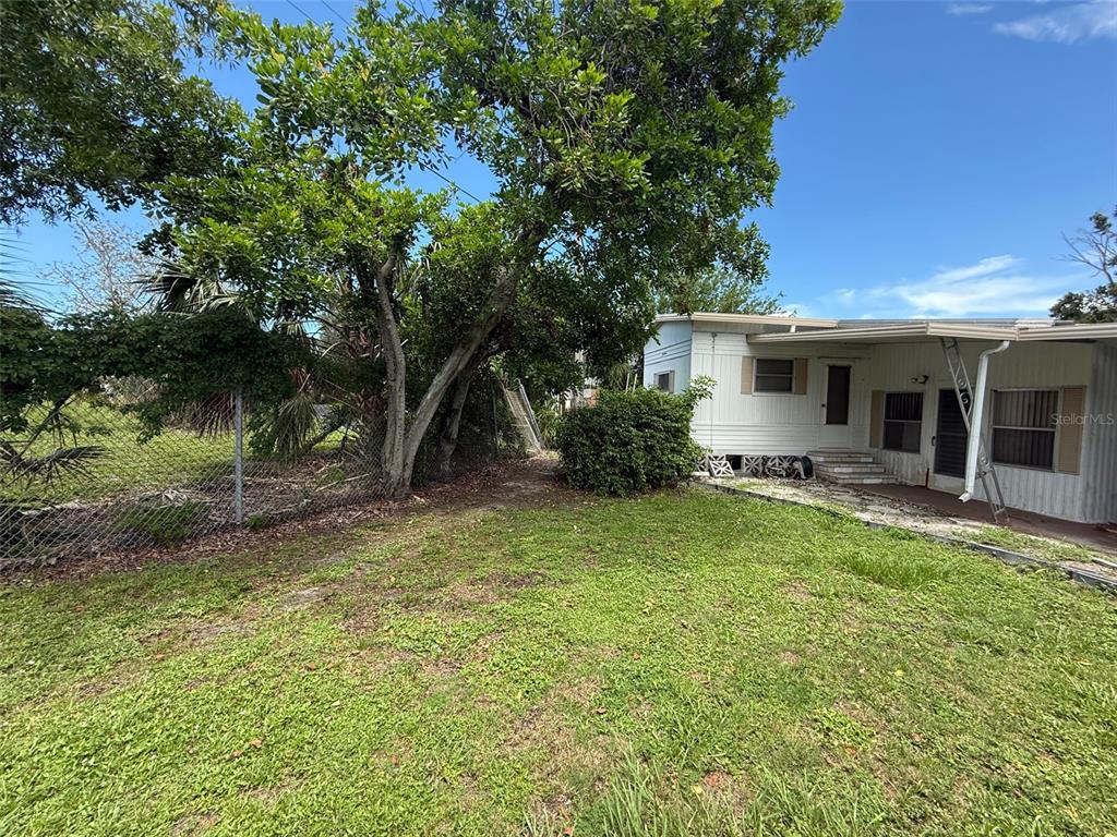 A white mobile home sits next to a large tree and a chain-link fence — 4845 BOCA RATON AVENUE, SARASOTA, FL