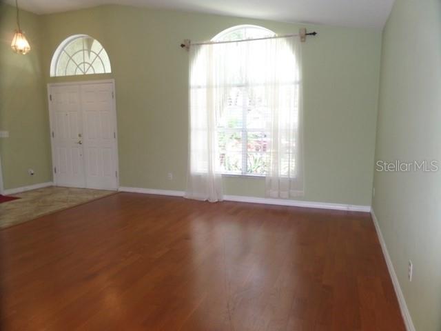 A living room features light green walls, hardwood floors, and a large arched window — 2631 FALLBROOK DRIVE, OVIEDO, FL