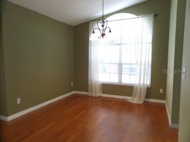 A dining room with olive walls, hardwood floors, a chandelier, and a large arched window — 2631 FALLBROOK DRIVE, OVIEDO, FL