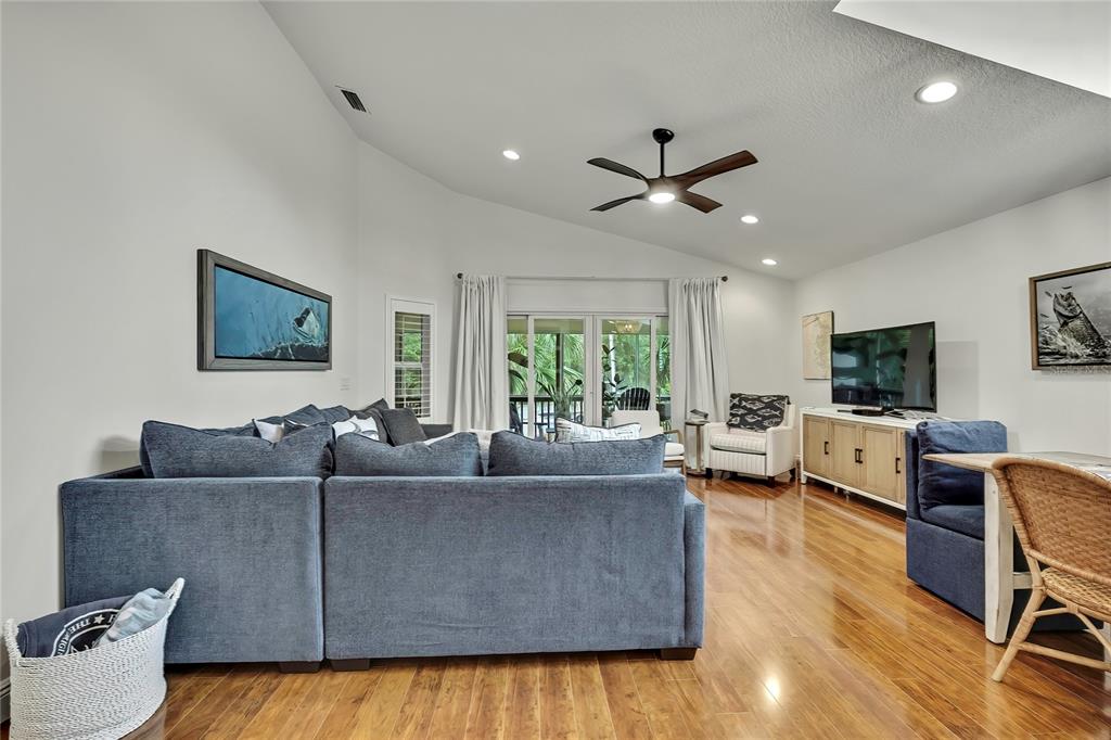 A living room features a large blue sectional sofa, hardwood floors, and a vaulted ceiling — 11956 W BLUE BAYOU COURT, CRYSTAL RIVER, FL