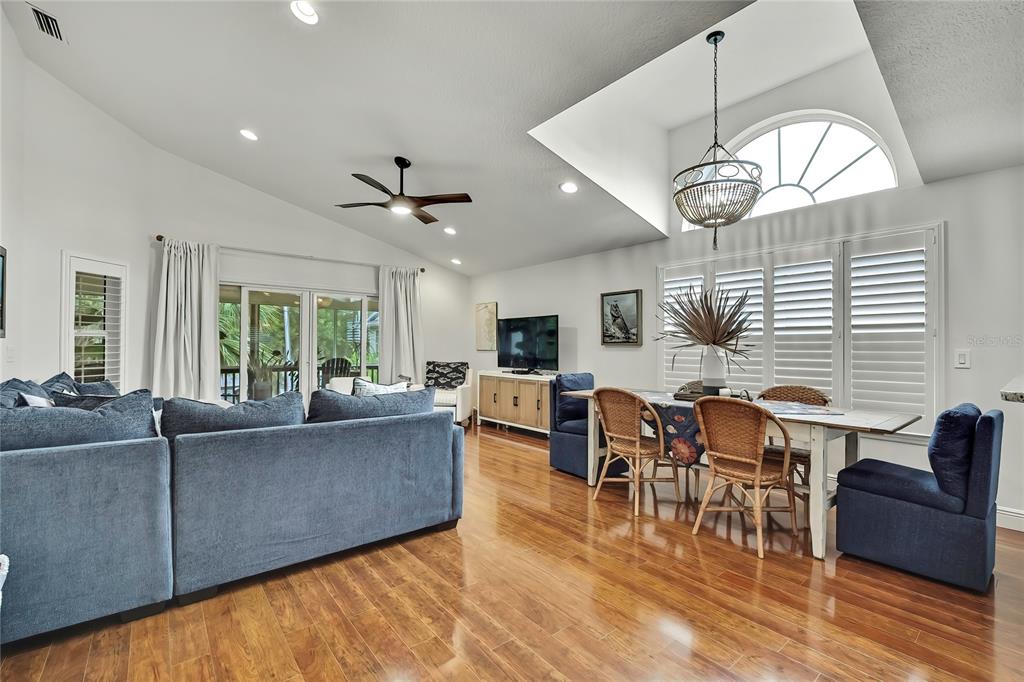 A living and dining area with hardwood floors, a vaulted ceiling, and a ceiling fan — 11956 W BLUE BAYOU COURT, CRYSTAL RIVER, FL