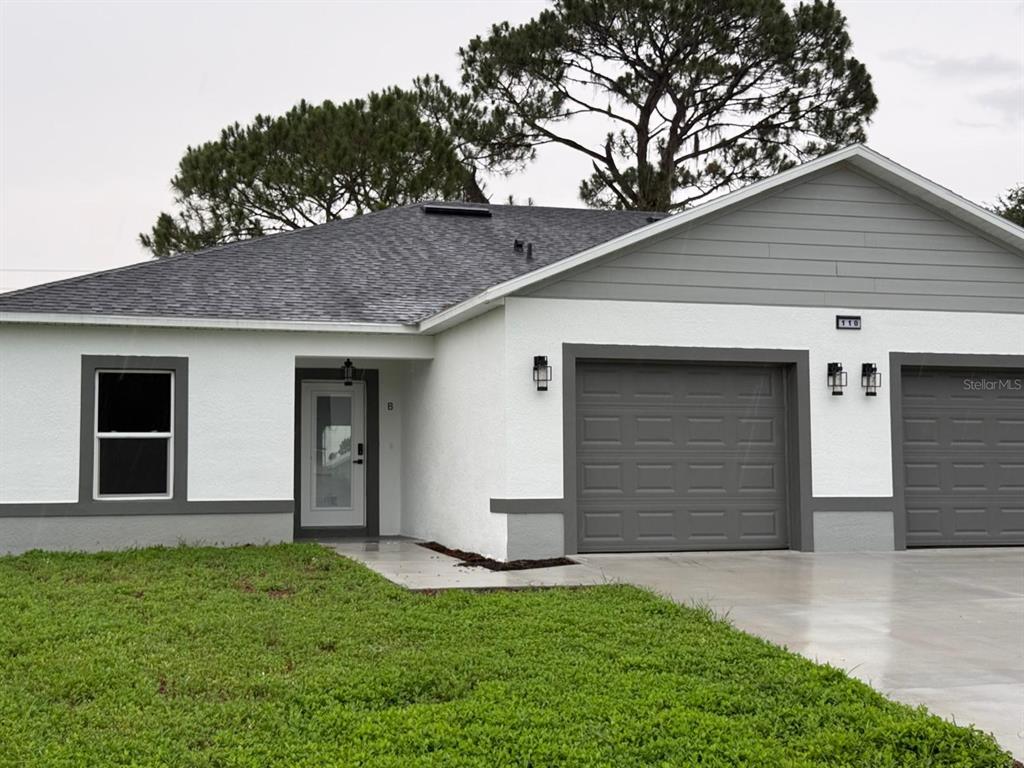 A white single-story duplex with gray trim, two garage doors, and a front lawn — 110 FRIENDLY CIRCLE UNIT 1, SEBRING, FL