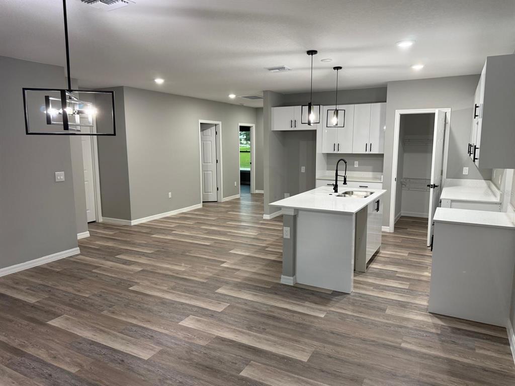 A kitchen with white cabinets, a center island, and wood-look flooring in an open-concept space — 110 FRIENDLY CIRCLE UNIT 1, SEBRING, FL