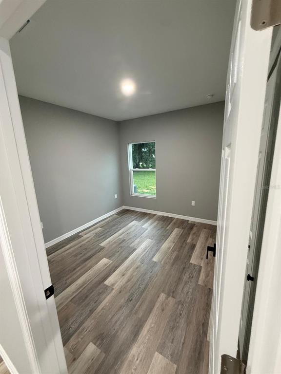 An empty bedroom with gray walls, wood-look flooring, and a single window — 110 FRIENDLY CIRCLE UNIT 1, SEBRING, FL