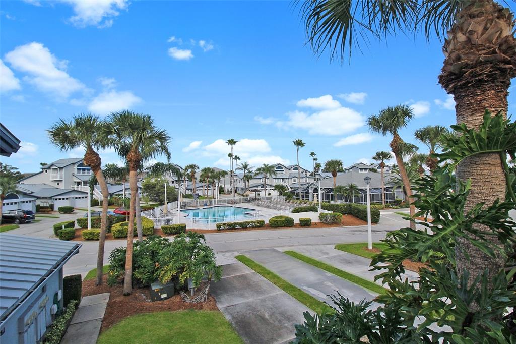 An outdoor view of a residential community featuring a swimming pool, palm trees, and houses — 1338 SIESTA BAYSIDE DRIVE UNIT 1338-C, SARASOTA, FL