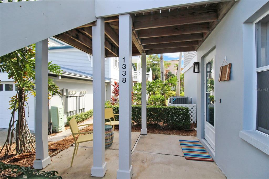 A covered patio features two yellow chairs, a small table, and a striped welcome mat — 1338 SIESTA BAYSIDE DRIVE UNIT 1338-C, SARASOTA, FL