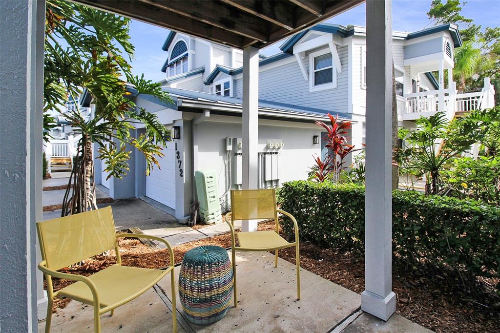 A patio with two yellow chairs and a colorful stool sits outside a light blue house — 1338 SIESTA BAYSIDE DRIVE UNIT 1338-C, SARASOTA, FL