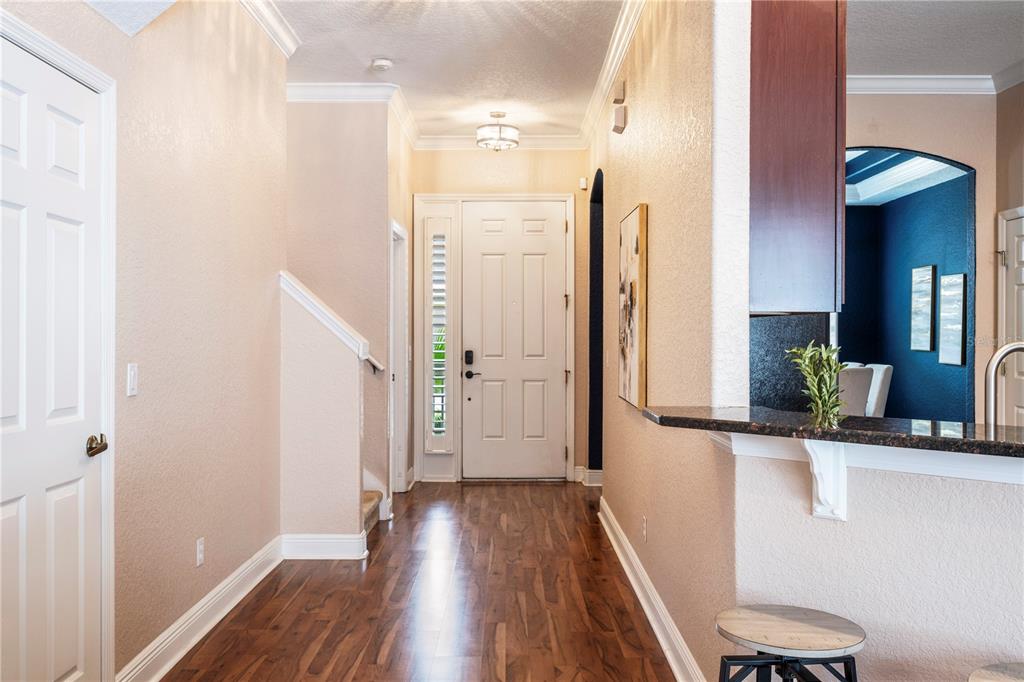 An entryway with wood flooring, a white front door, and a kitchen breakfast bar — 573 SHINING ARMOR LANE, LONGWOOD, FL