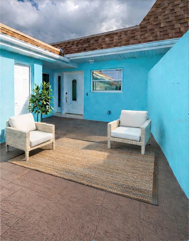 A patio with two wicker chairs and a rug sits against a bright blue wall — 350 BOCA CIEGA POINT BLVD, ST PETERSBURG, FL