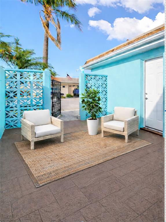 Two wicker chairs sit on a rug on a patio outside a blue building — 350 BOCA CIEGA POINT BLVD, ST PETERSBURG, FL