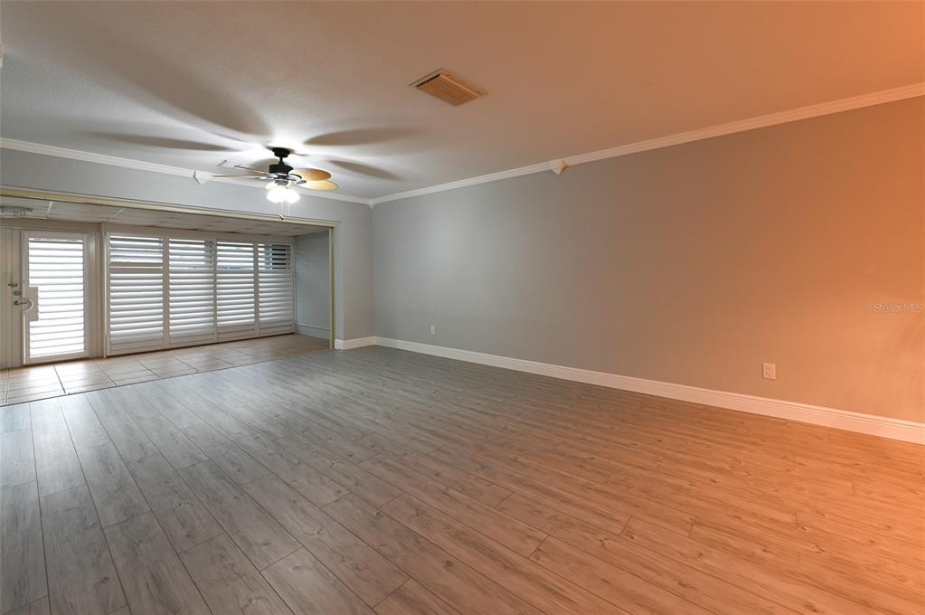 An empty living room features light wood-look flooring, gray walls, and a ceiling fan — 350 BOCA CIEGA POINT BLVD, ST PETERSBURG, FL