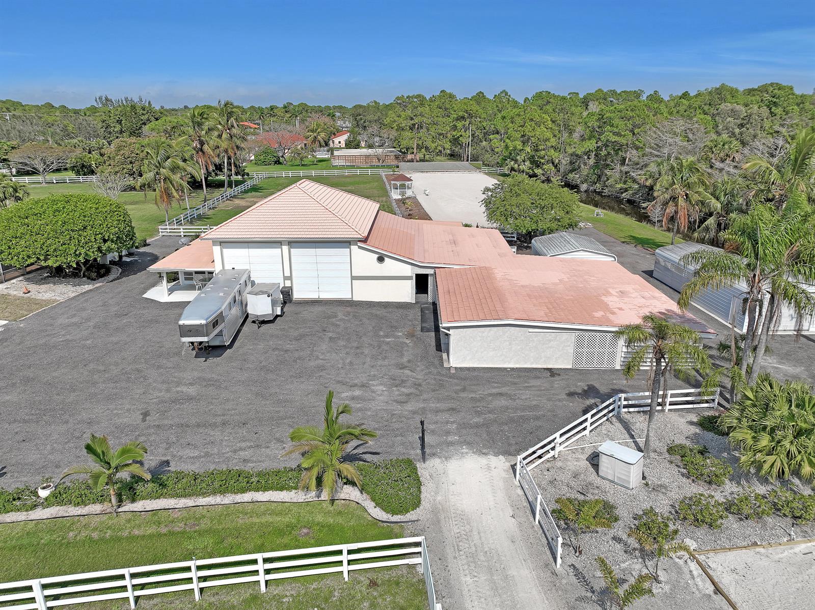 An aerial view shows a large building with a red roof, gravel driveway, and stables — 3426 &3406 Hanover Circle, Loxahatchee FL 33470, LOXAHATCHEE, FL