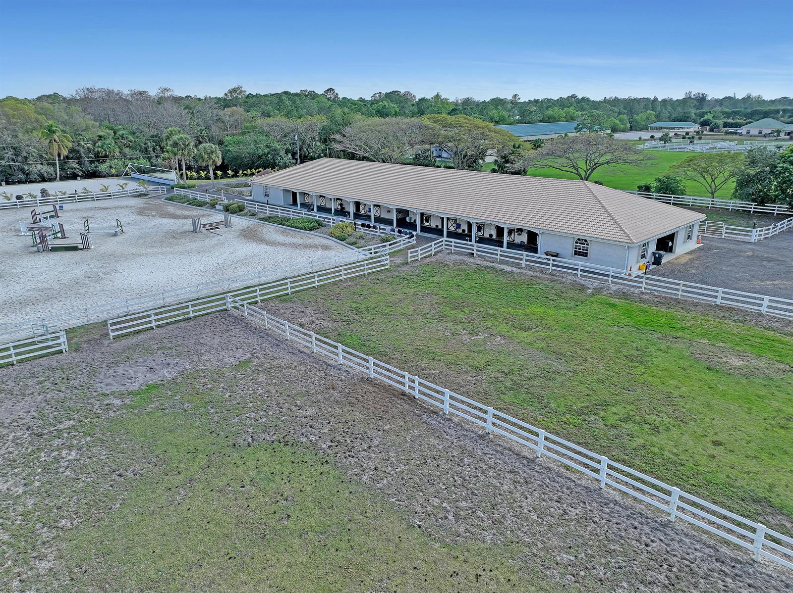 An aerial view shows a long horse stable building next to a fenced riding arena — 3426 &3406 Hanover Circle, Loxahatchee FL 33470, LOXAHATCHEE, FL