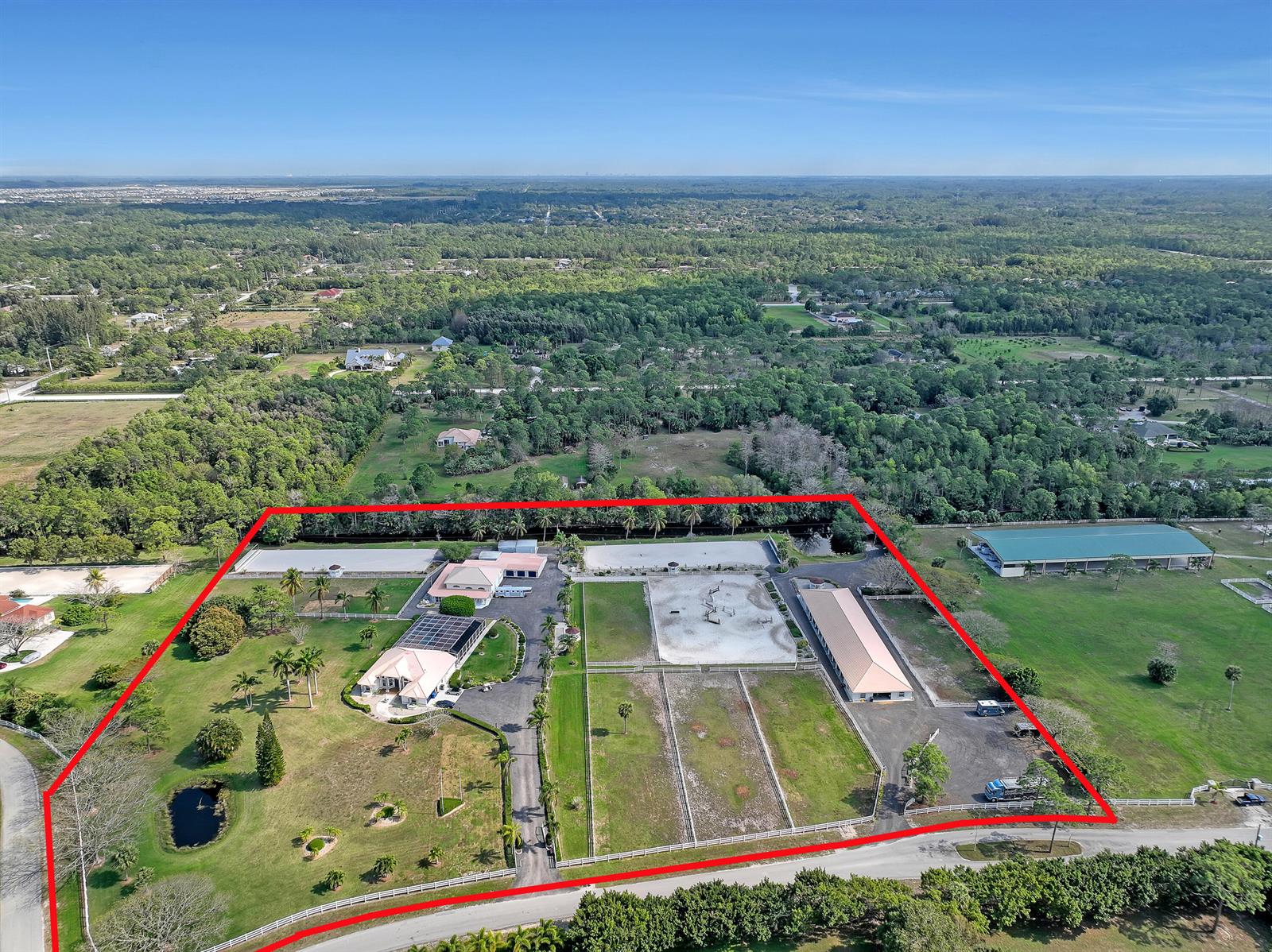 An aerial view shows a residential estate with a house, stables, and riding arenas — 3426 &3406 Hanover Circle, Loxahatchee FL 33470, LOXAHATCHEE, FL