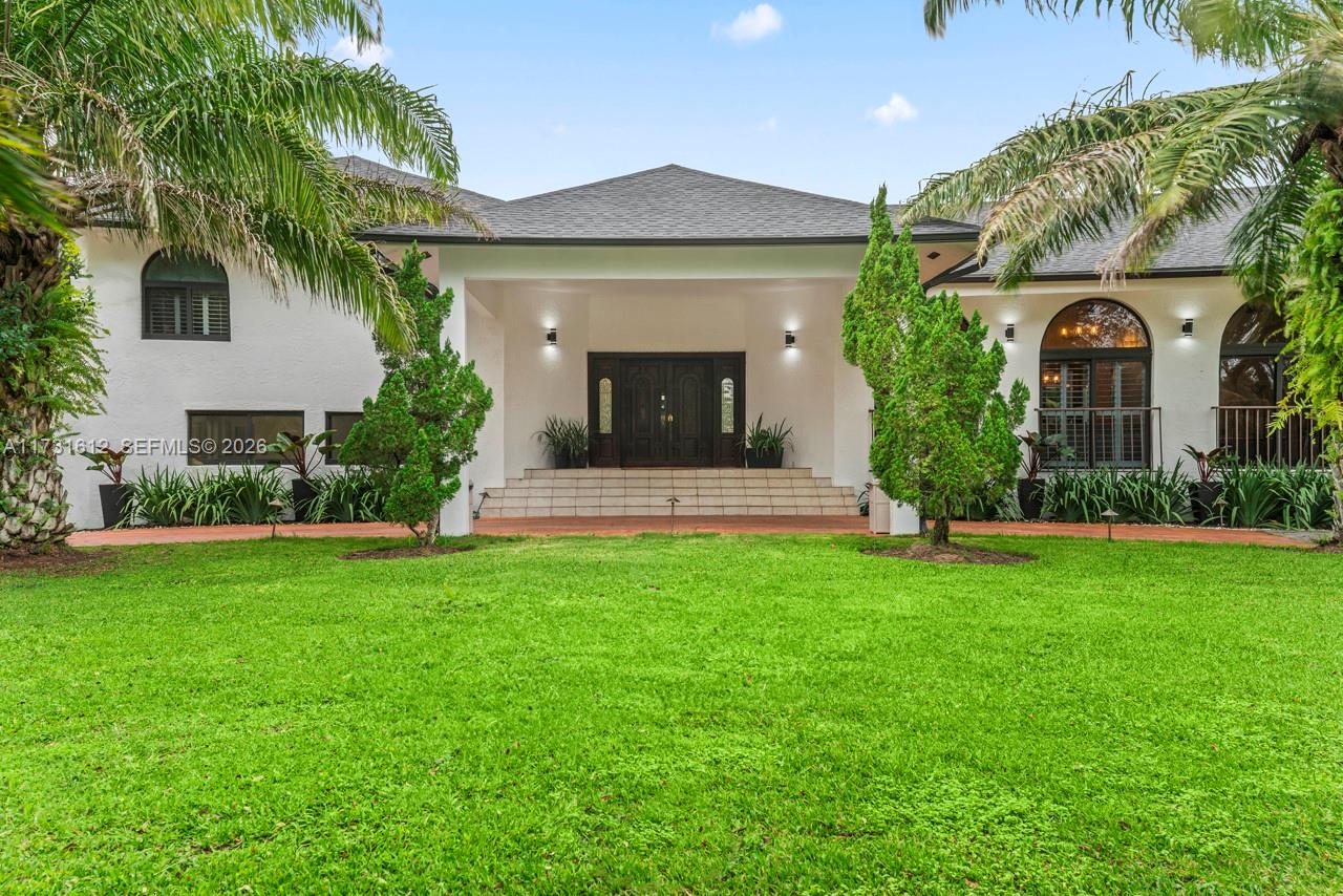 A white single-story house features a covered entryway with double doors and arched windows — 14875 SW 212th St, Miami FL 33187, MIAMI, FL