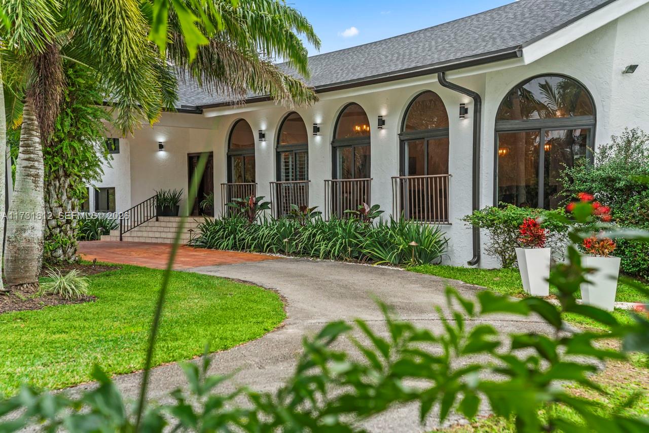 A white house exterior features arched windows, a tiled patio, and a curved driveway — 14875 SW 212th St, Miami FL 33187, MIAMI, FL