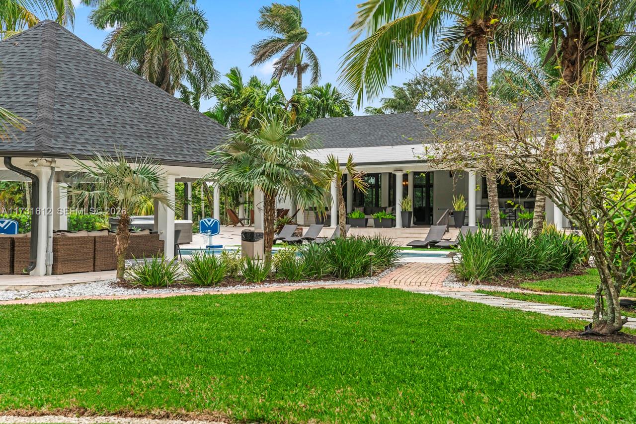 A backyard features a swimming pool, a covered patio, and a lawn with palm trees — 14875 SW 212th St, Miami FL 33187, MIAMI, FL