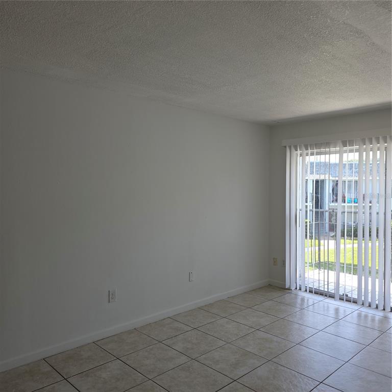 An empty room with white walls, tiled flooring, and a sliding glass door to a balcony — 921 W OAK RIDGE ROAD UNIT 921C, ORLANDO, FL