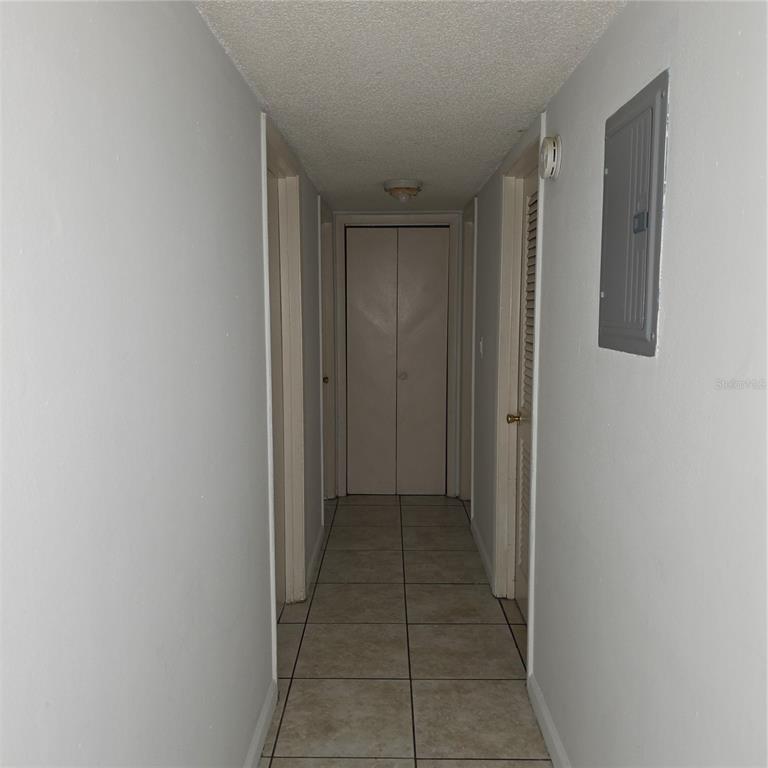 A narrow hallway with light-colored tile flooring, white walls, and a closed closet door — 921 W OAK RIDGE ROAD UNIT 921C, ORLANDO, FL
