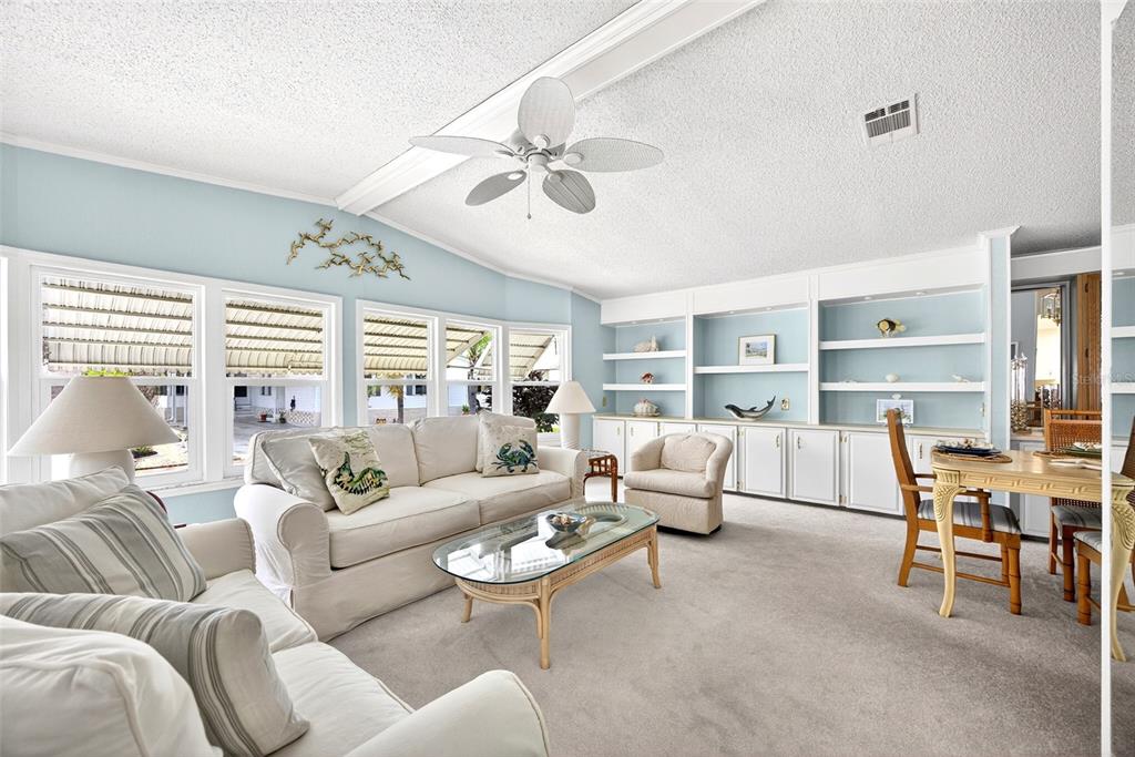 A living room with light blue walls, white built-in shelving, a sofa, and a ceiling fan — 15550 BURNT STORE ROAD UNIT 164, PUNTA GORDA, FL