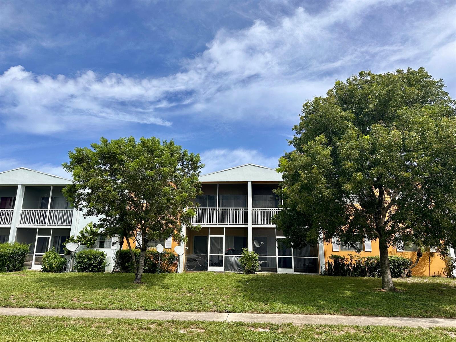 A two-story apartment building with screened balconies and trees in front under a blue sky — 1505 CRESCENT Circle # A12, Lake Park FL 33403, LAKE PARK, FL