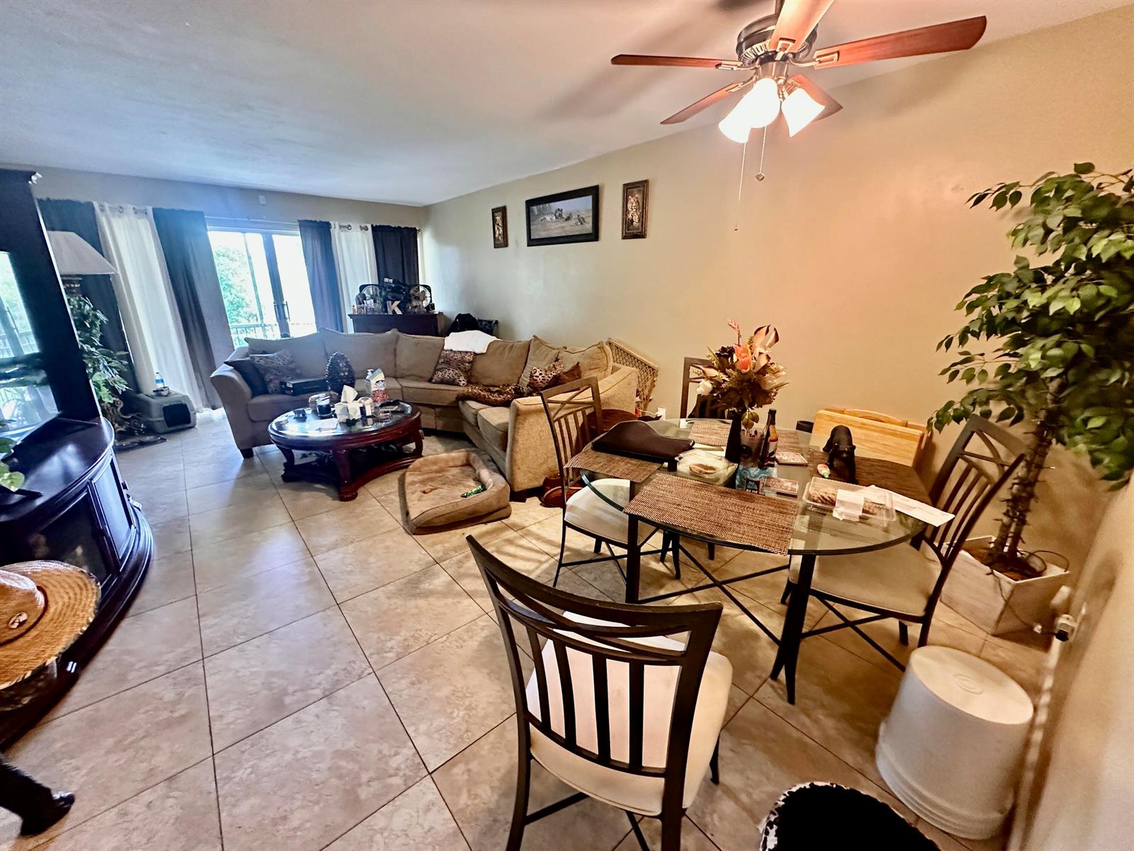 An open-concept living and dining area features tile flooring, a sectional sofa, and glass-topped table — 1505 CRESCENT Circle # A12, Lake Park FL 33403, LAKE PARK, FL