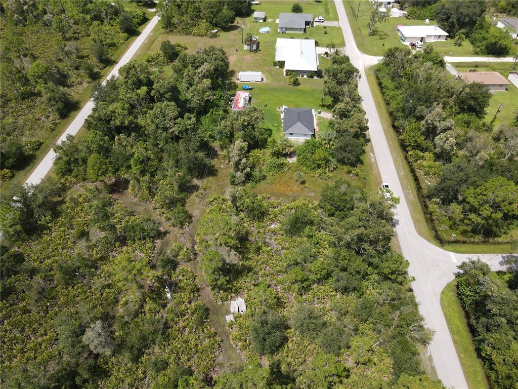 An aerial view shows a residential property with a house, outbuildings, and surrounding wooded land — 27487 SENATOR DRIVE, PUNTA GORDA, FL