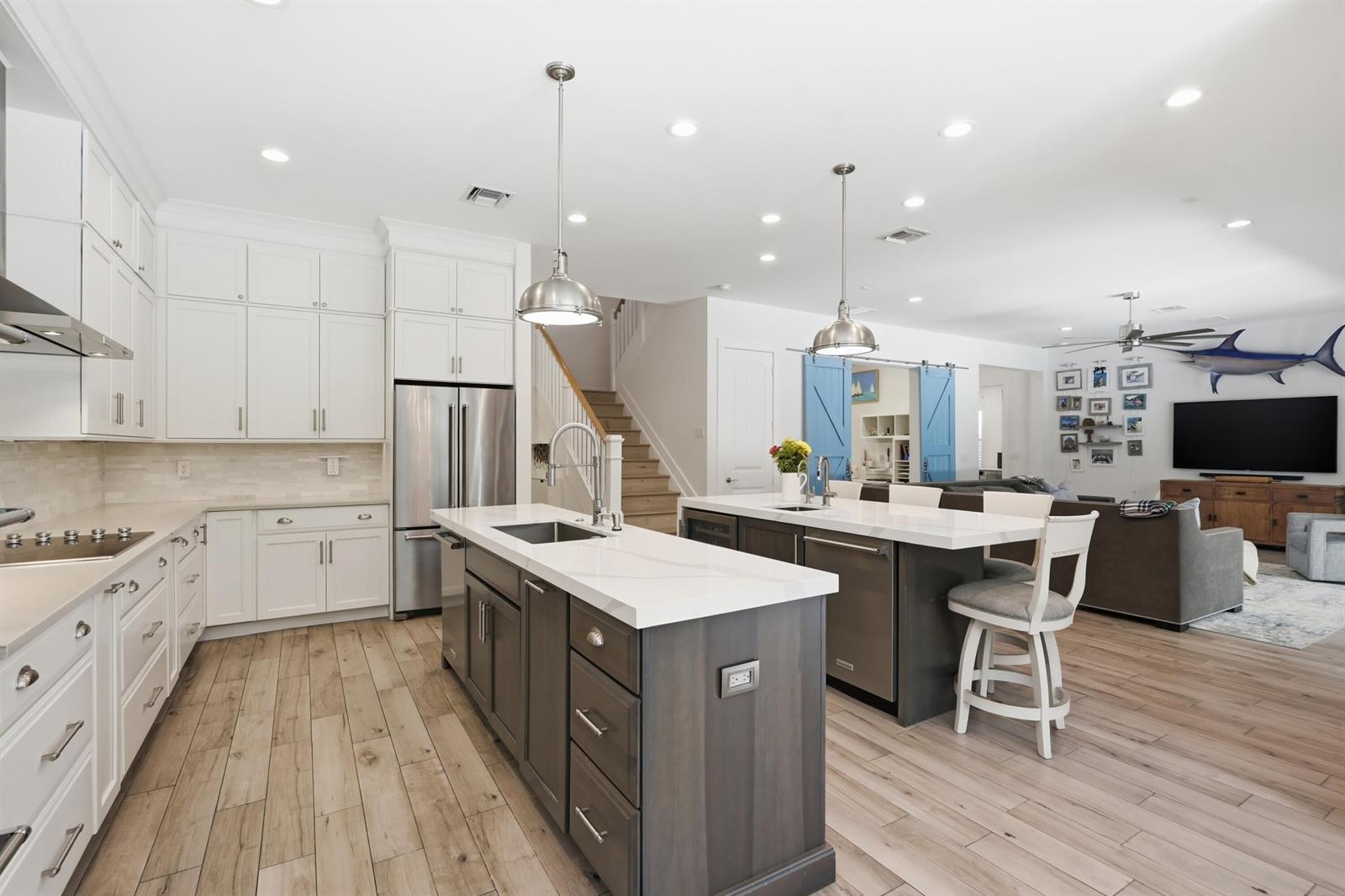 A kitchen features two dark wood islands, white cabinetry, stainless steel appliances, and light wood flooring — 2840 NE 22nd Avenue, Lighthouse Point FL 33064, LIGHTHOUSE POINT, FL