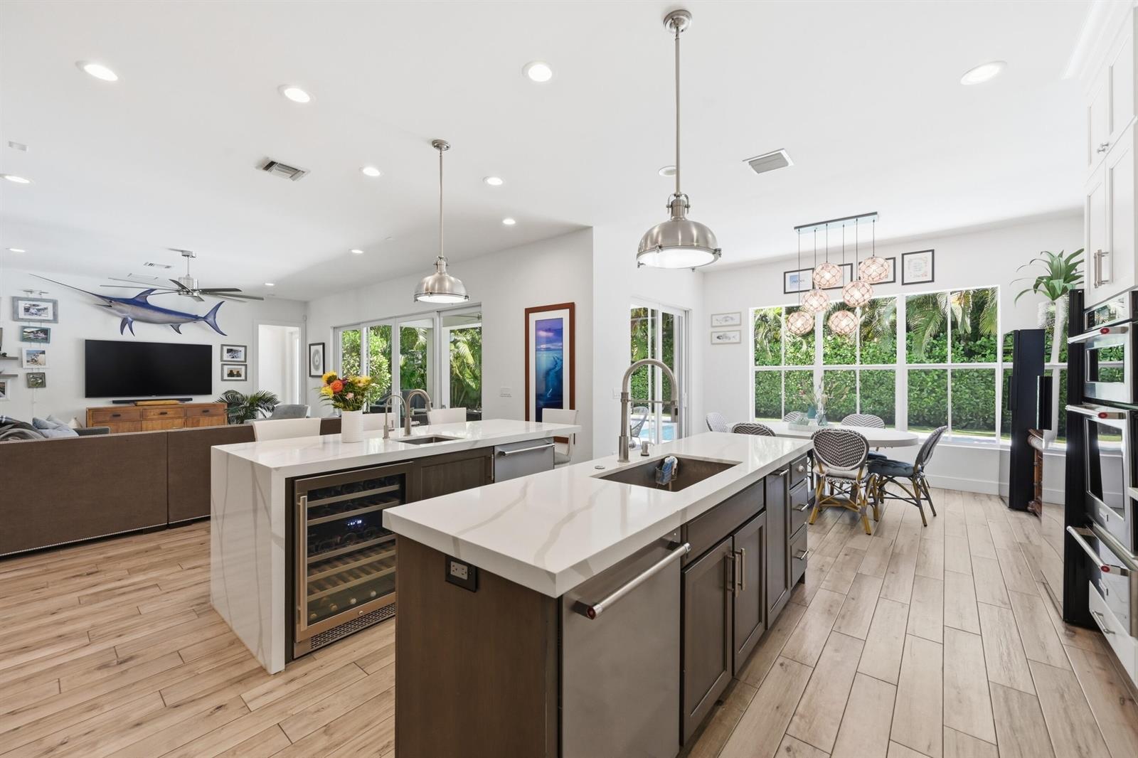 A modern kitchen features two islands with white countertops, dark cabinetry, and wood-look tile flooring — 2840 NE 22nd Avenue, Lighthouse Point FL 33064, LIGHTHOUSE POINT, FL